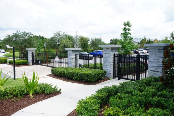 black metal fence and gate with stone pillars around parking lot